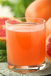 Photo of Glass of delicious grapefruit juice on table, closeup