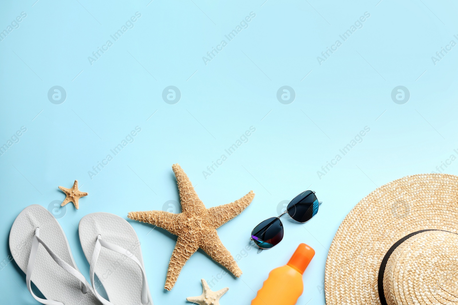 Photo of Beach accessories on light blue background, flat lay. Space for text