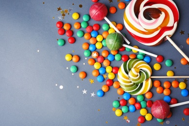 Photo of Lollipops and colorful candies on grey background, top view. Space for text
