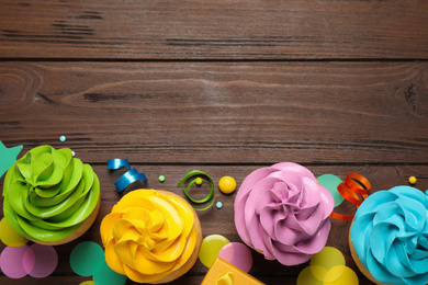 Flat lay composition with colorful birthday cupcakes on wooden table. Space for text