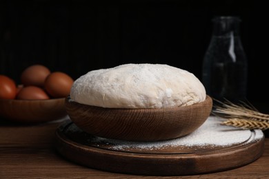 Photo of Dough in bowl on wooden table against black background. Sodawater bread recipe