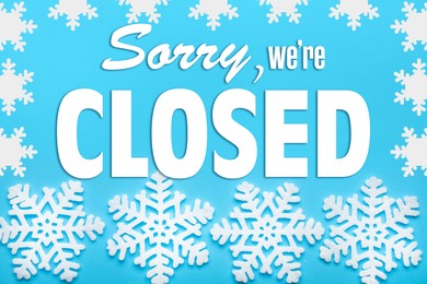 Image of Sorry we are closed sign. Text and snowflakes on light blue background