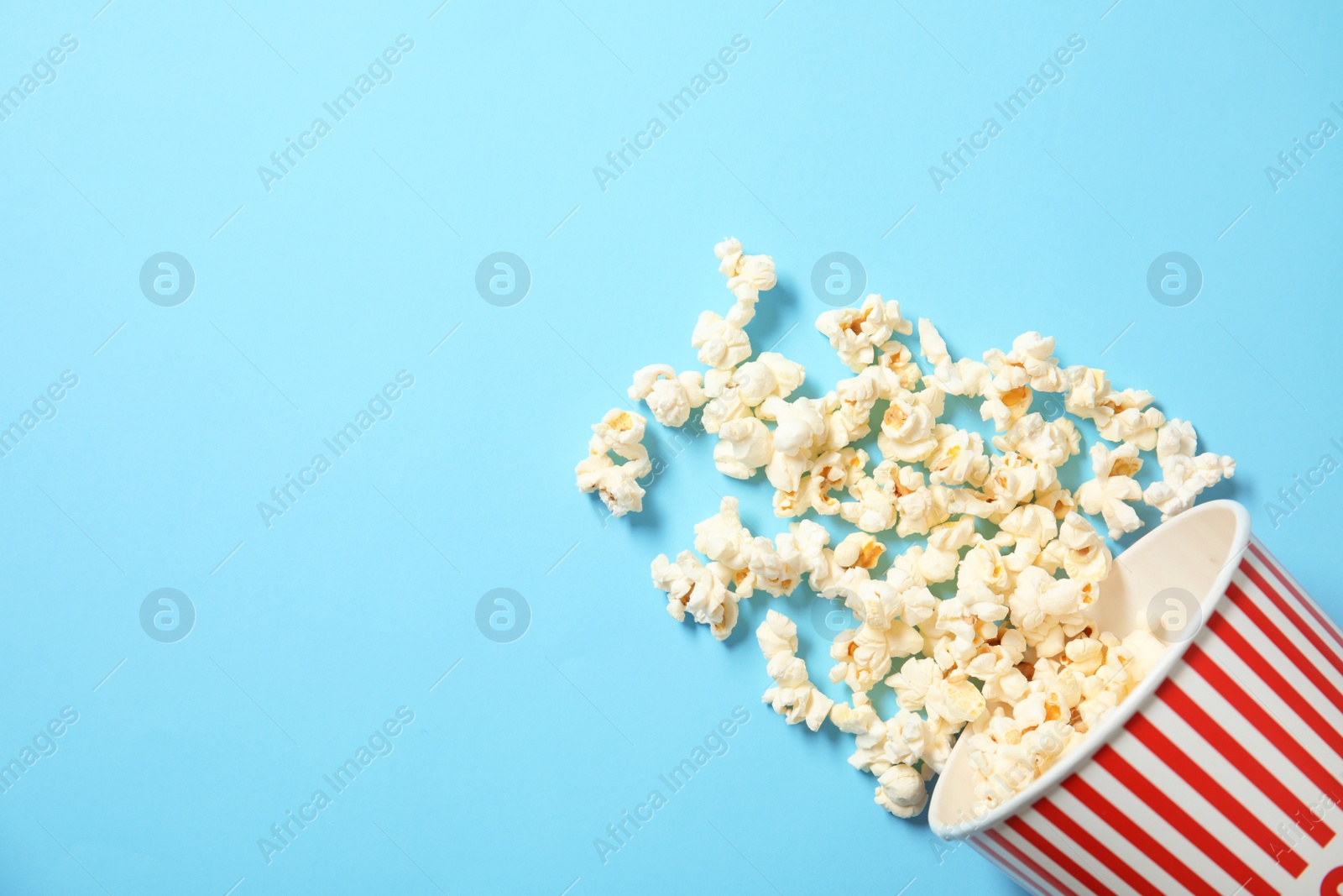 Photo of Cup with fresh tasty popcorn on color background, top view. Cinema snack