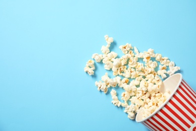 Cup with fresh tasty popcorn on color background, top view. Cinema snack