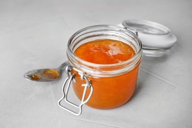 Photo of Jar and spoon with sweet jam on light background