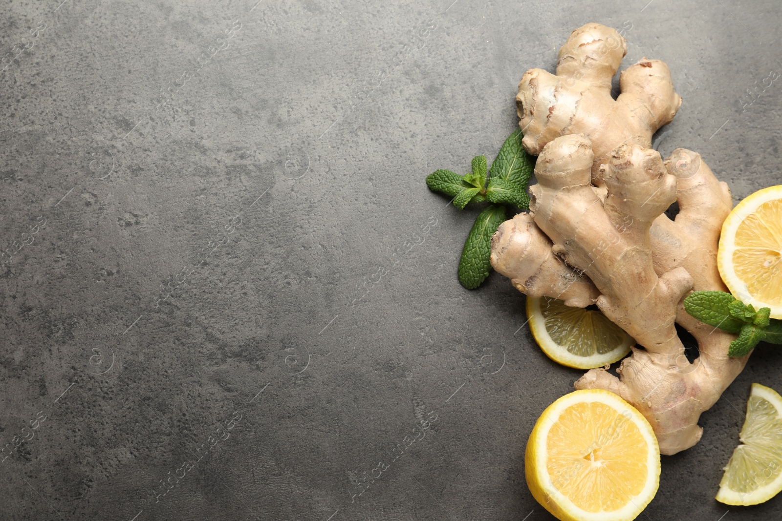 Photo of Fresh lemon, ginger and mint on grey table, flat lay. Space for text