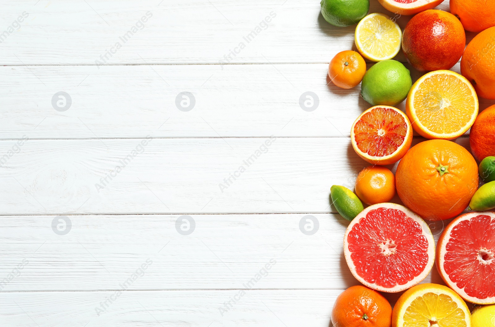 Photo of Flat lay composition with different citrus fruits and space for text on white wooden background