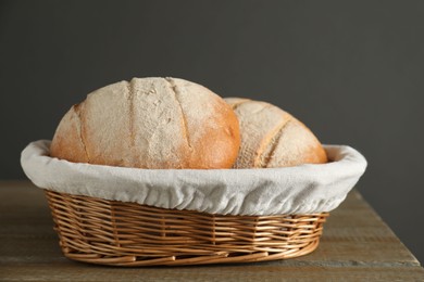 Photo of Wicker basket with fresh bread on wooden table, closeup