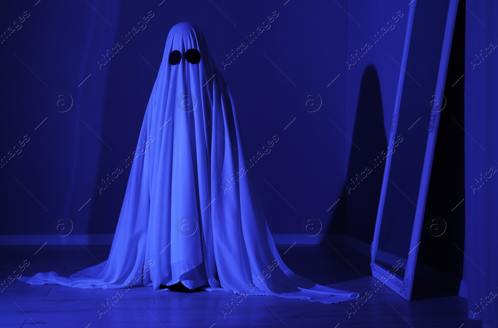 Photo of Creepy ghost. Woman covered with sheet in blue light