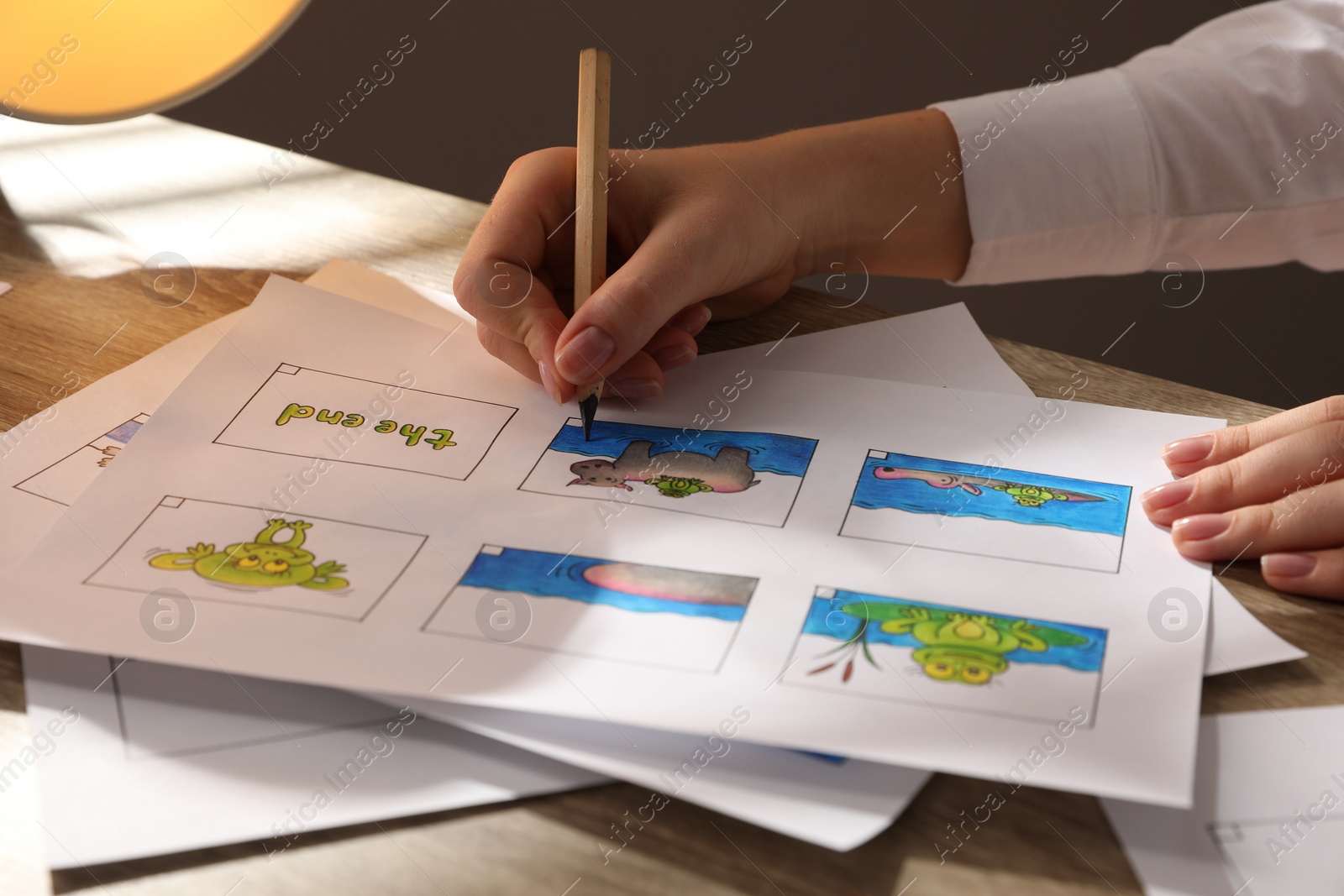 Photo of Woman drawing cartoon sketch in storyboard at workplace, closeup. Pre-production process