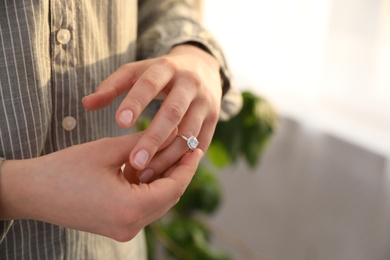 Photo of Woman taking off wedding ring indoors, closeup with space for text. Divorce concept