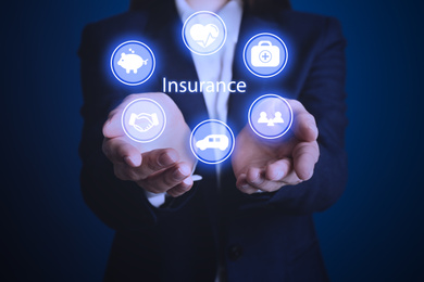 Image of Businesswoman holding different icons on dark blue background, closeup. Insurance concept