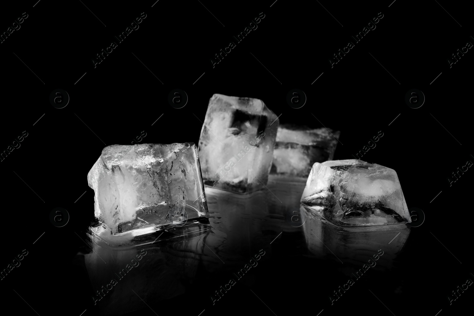 Photo of Transparent ice cubes on black mirror surface