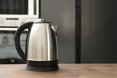 Photo of Modern electric kettle on table in kitchen. Space for text