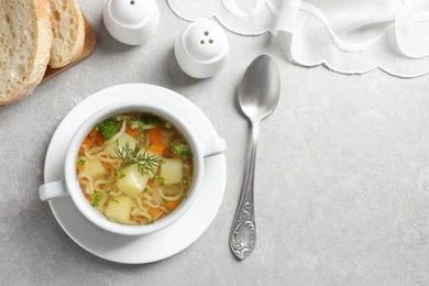 Photo of Dish of fresh homemade vegetable soup served on light grey table, flat lay. Space for text