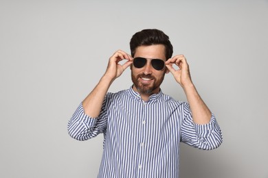 Photo of Portrait of smiling bearded man with sunglasses on grey background