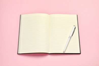 Photo of Open planner with pen on colorful background, above view