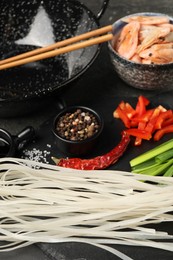 Photo of Different products and wok with chopsticks on dark table, closeup