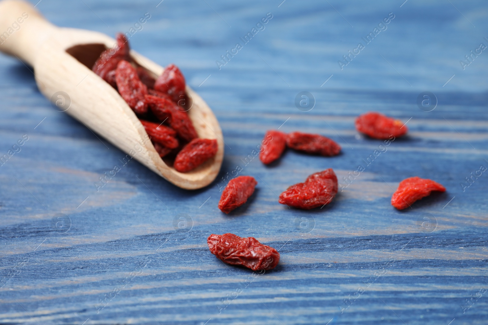 Photo of Dried goji berries on blue wooden table, closeup