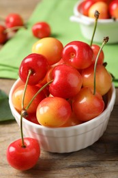 Sweet red cherries in bowl on wooden table