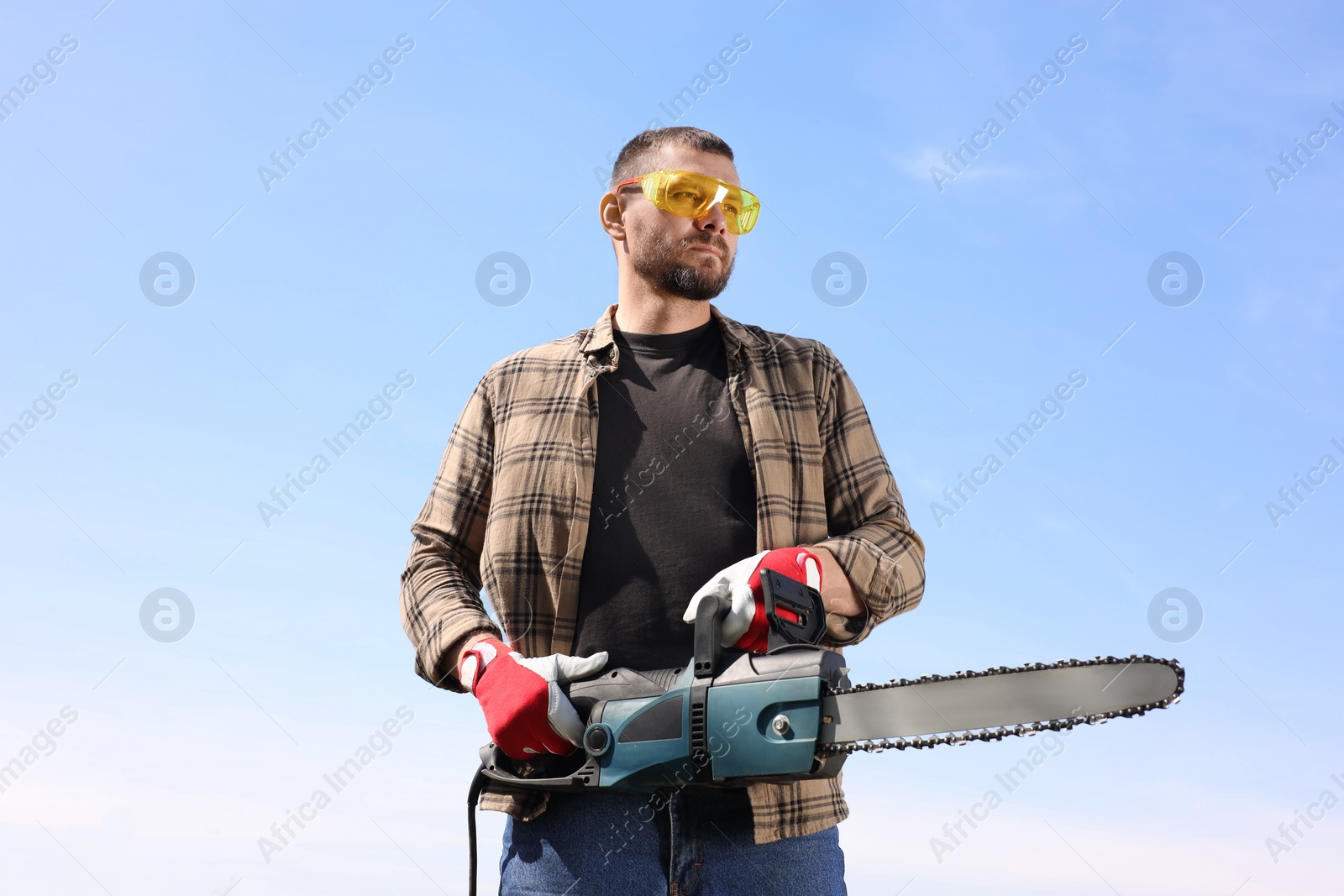 Photo of Man with modern saw against blue sky, low angle view