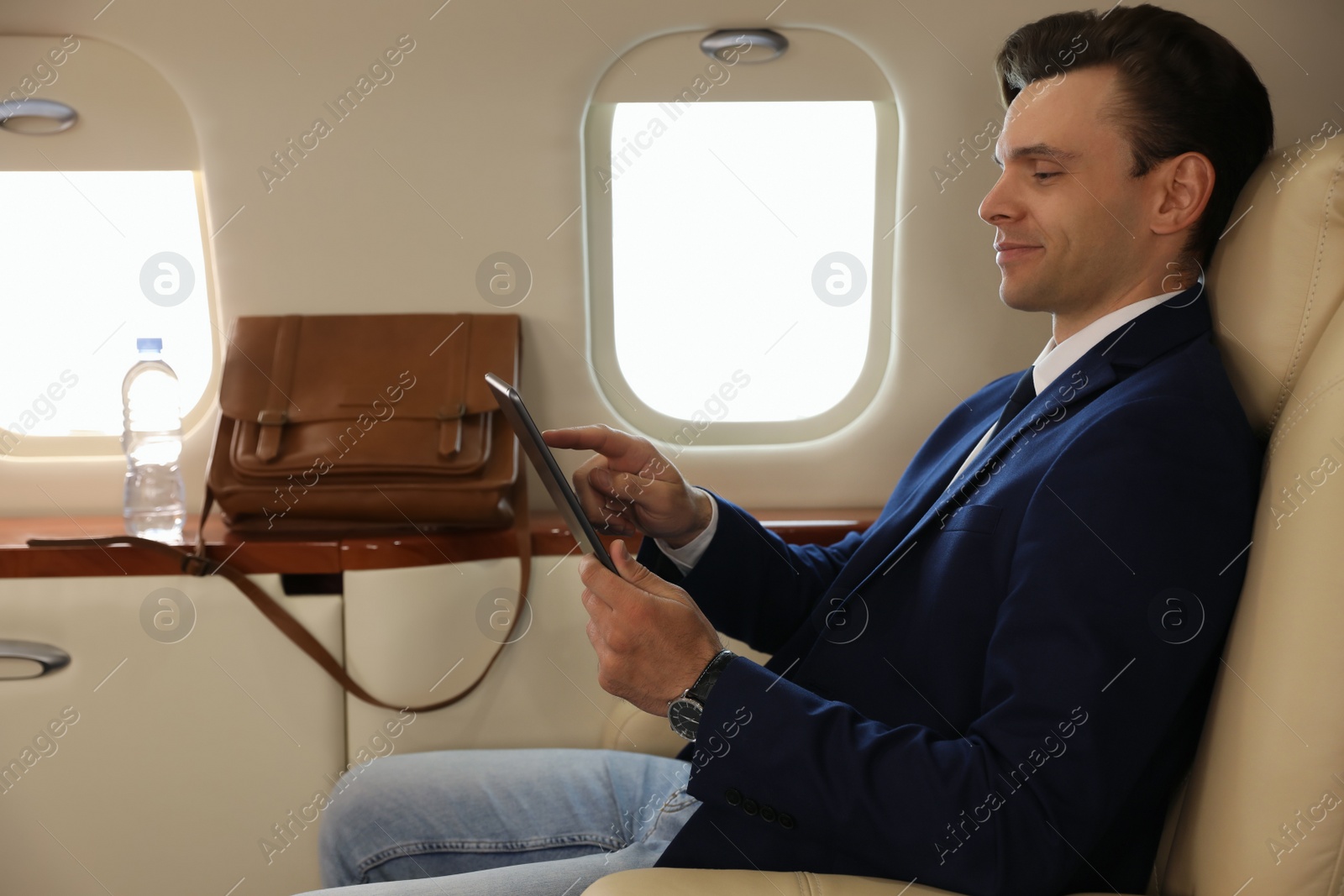 Photo of Businessman working on tablet in airplane during flight