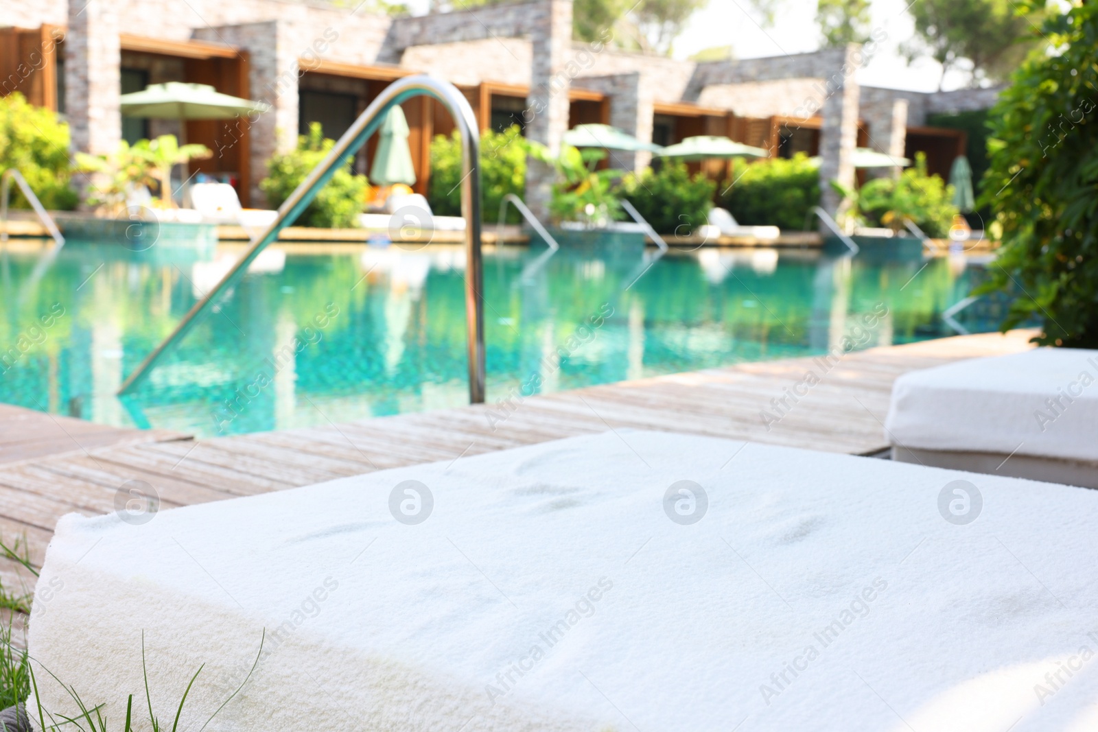 Photo of Outdoor swimming pool with wooden deck and sun loungers. Luxury resort