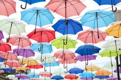 Photo of Many opened multicolored umbrellas on light background