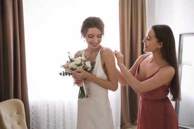 Photo of Gorgeous bride in beautiful wedding dress and her friend in room