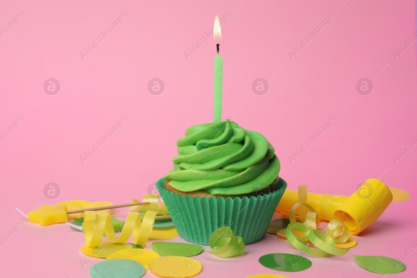 Photo of Delicious birthday cupcake with green cream and burning candle on pink background