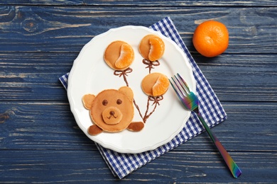 Photo of Flat lay composition with pancakes in form of bear holding balloons on wooden background. Creative breakfast ideas for kids