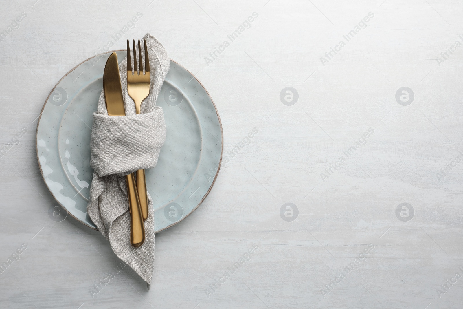 Photo of Stylish setting with cutlery, napkin and plates on white table, top view. Space for text