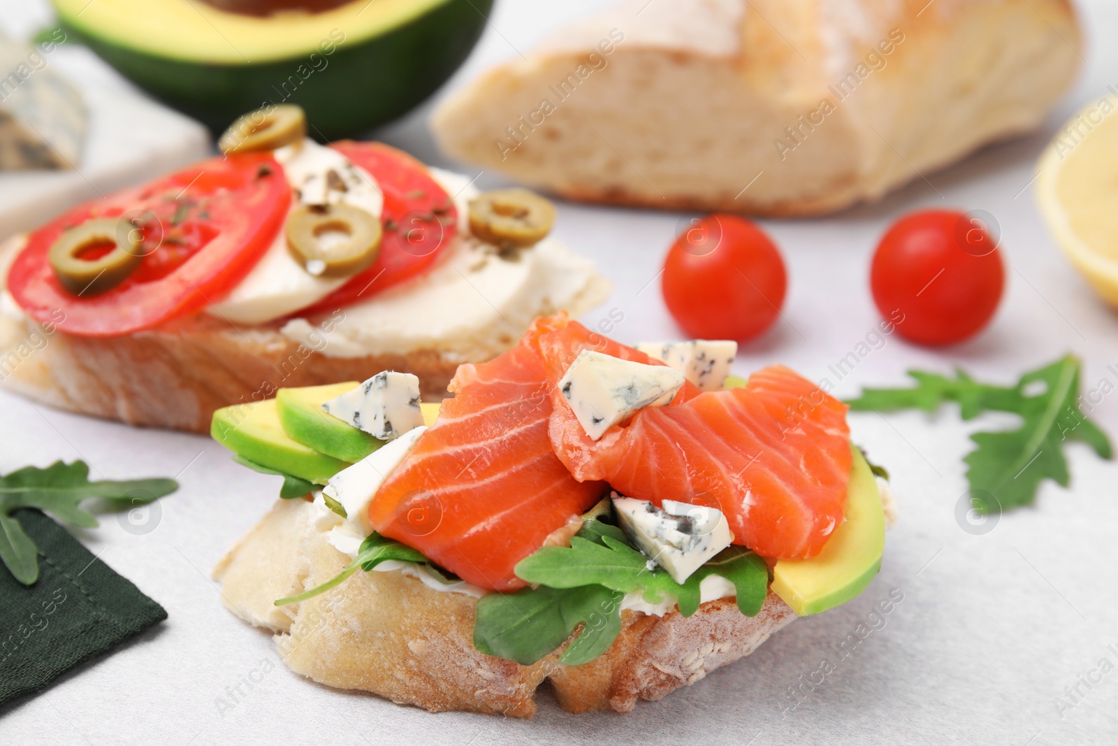 Photo of Different tasty bruschettas and ingredients on light grey textured table, closeup