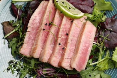Photo of Pieces of delicious tuna steak with salad on plate, closeup