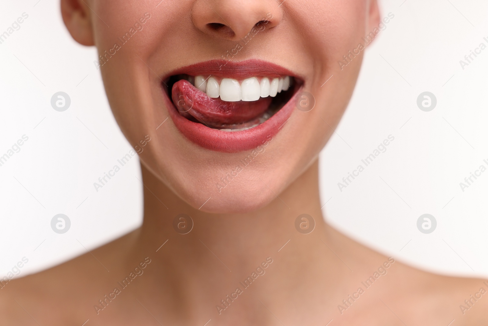 Photo of Woman with beautiful lips licking her teeth on white background, closeup