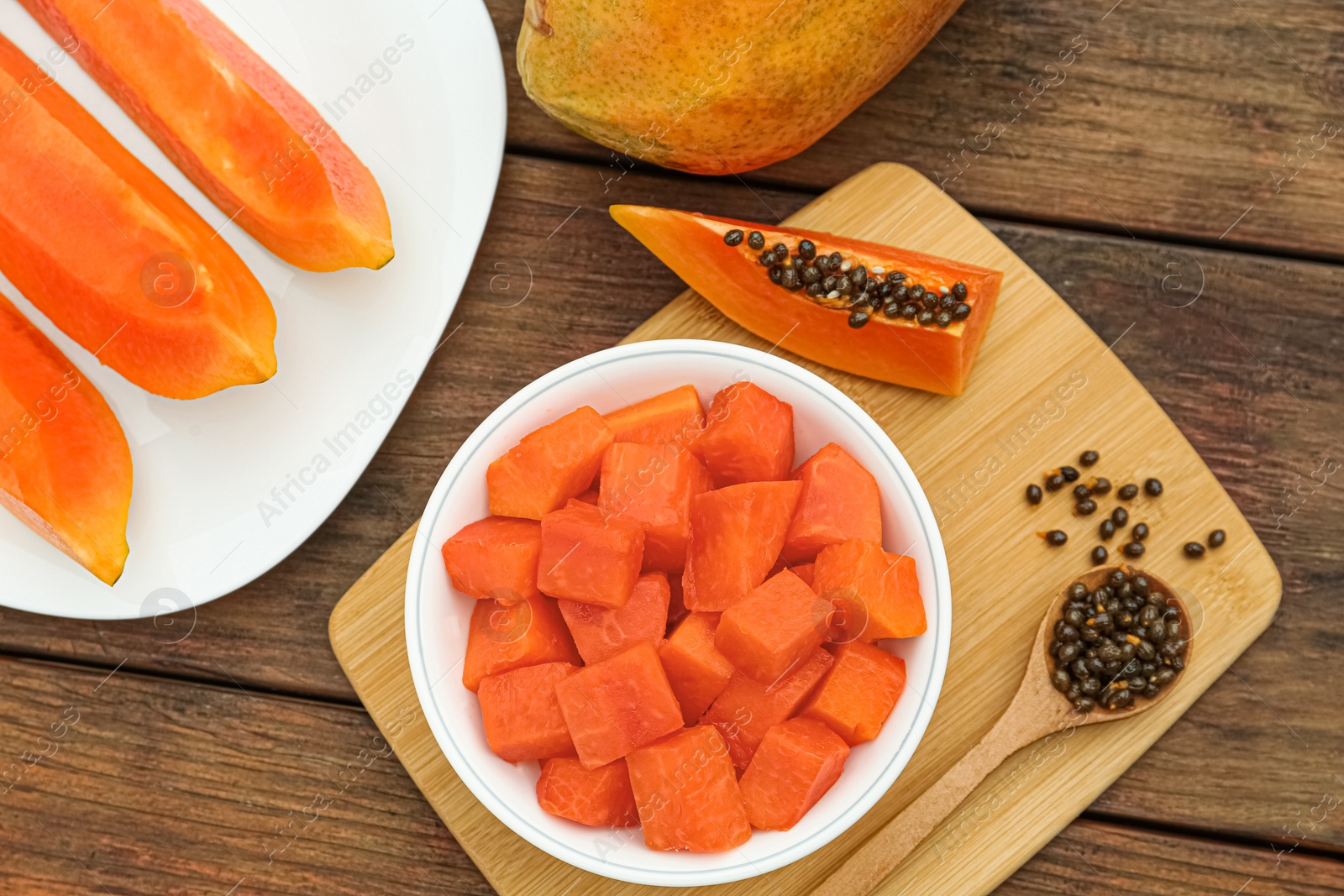 Photo of Tasty cut papaya fruits on wooden table, flat lay