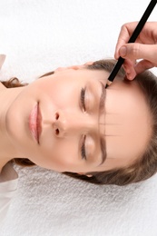 Young woman having eyebrow correction procedure in beauty salon