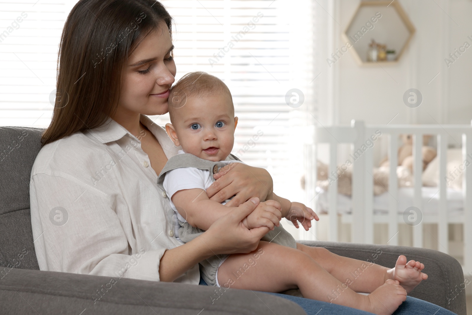 Photo of Happy young mother with her baby in armchair at home