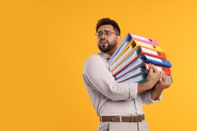 Photo of Stressful man with folders on orange background, space for text