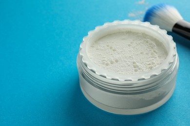 Photo of Rice loose face powder and makeup brush on light blue background, closeup. Space for text