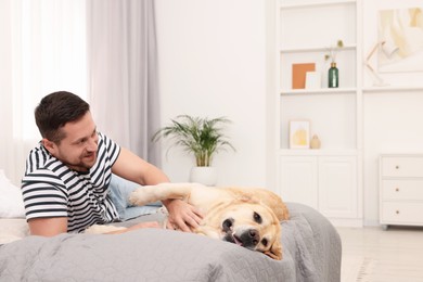 Photo of Man with adorable Labrador Retriever dog on bed at home, space for text. Lovely pet