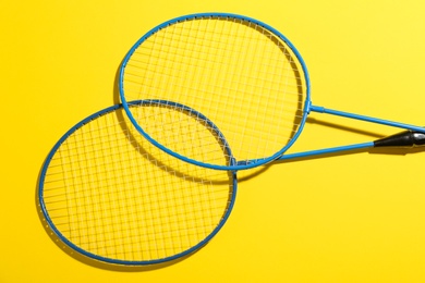 Photo of Badminton rackets on yellow background, above view