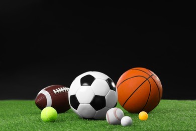 Photo of Many different sports balls on green grass against black background, space for text