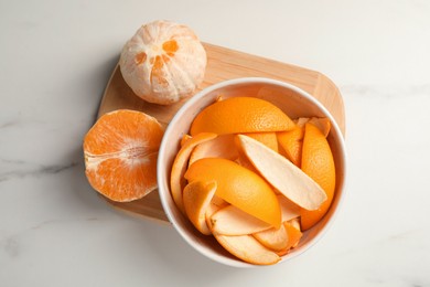Photo of Peeled fresh fruits and orange zest preparing for drying on white marble table, top view