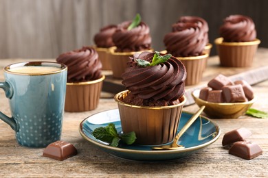 Photo of Delicious cupcakes with chocolate pieces and mint on wooden table