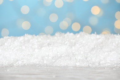 Photo of Heap of snow on wooden surface against blue background. Christmas season