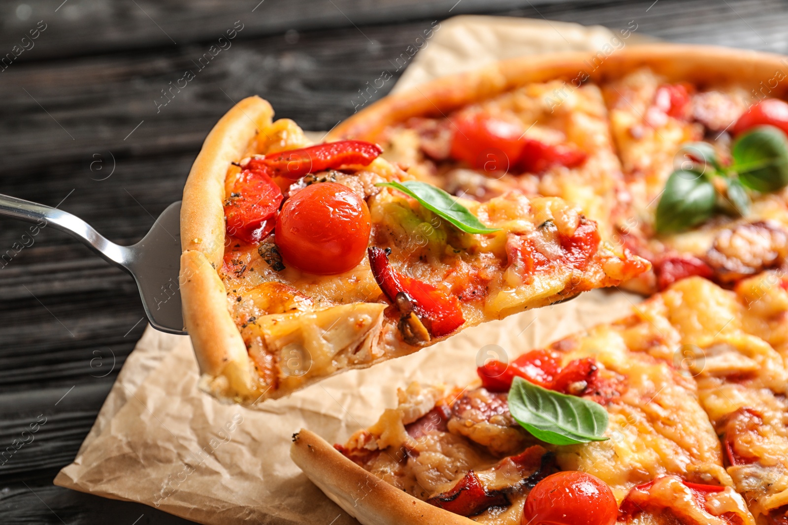 Photo of Slice of tasty pizza with tomatoes and sausages on shovel, closeup