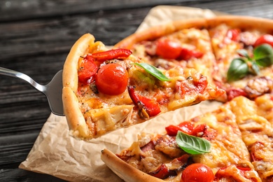 Photo of Slice of tasty pizza with tomatoes and sausages on shovel, closeup