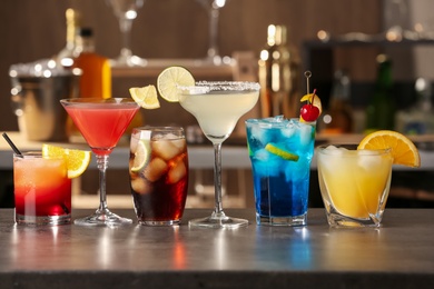 Photo of Different delicious cocktails on grey table in bar