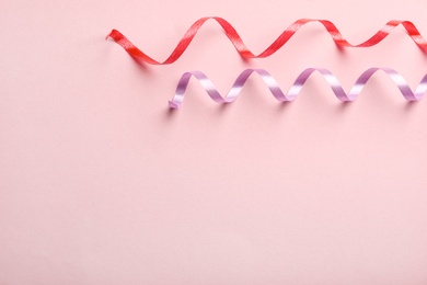 Colorful serpentine streamers on pink background, flat lay. Space for text